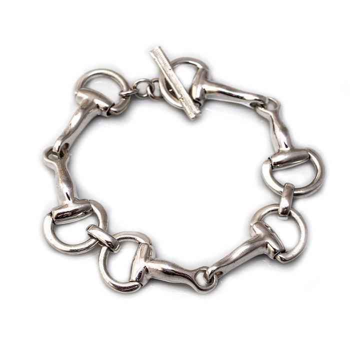 A sterling silver bracelet featuring a chunky chain design of horse bit snaffle bit, closing with a toggle.