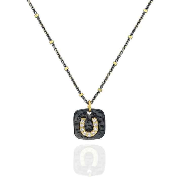 A Sterling Silver necklace featuring a small horseshoe charm with cubic zirconia set in 22k gold, suspended from a chain with small gold accents.