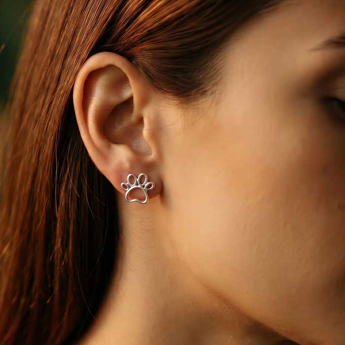 Outline Paw Print Post Earrings in Sterling Silver shown on woman