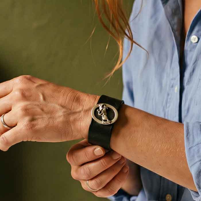 jumping horse and ride oval sterling silver on leather cuff bracelet on person's wrist