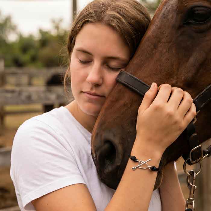 Sterling Silver Stirrup and Crop Toggle on Leather Bracelet on young woman holding horse