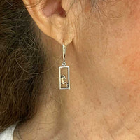 framed pair of horses dangle earring on ear