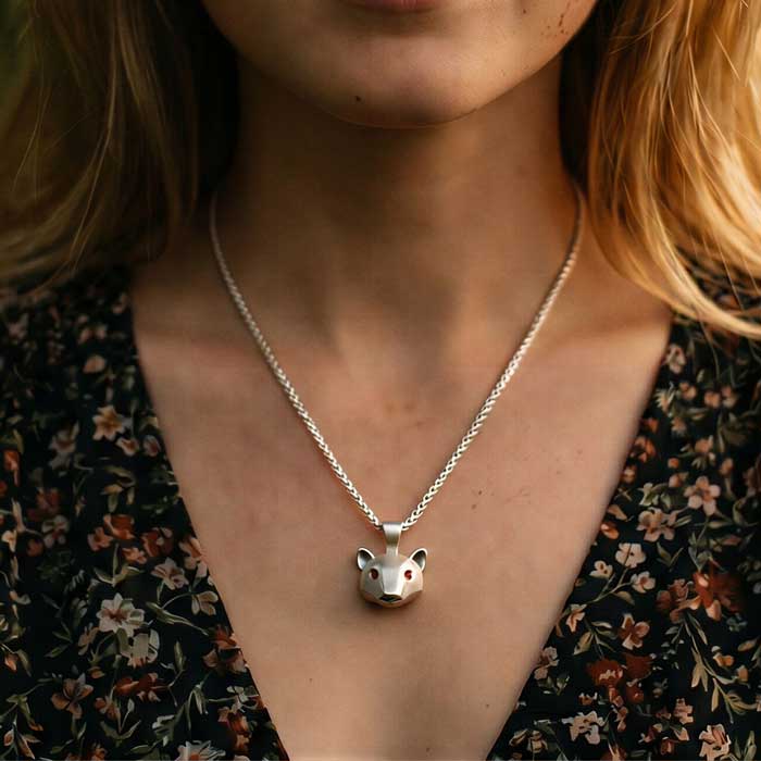 Grizzly Bear Pendant in Sterling Silver with gemstone eyes shown on neck of woman