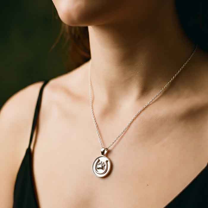 Sterling silver pendant with horseshoe and paw print shown on person's neck