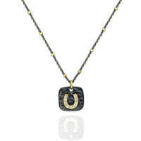 A Sterling Silver necklace featuring a small horseshoe charm with cubic zirconia set in 22k gold, suspended from a chain with small gold accents.