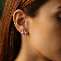 Outline Paw Print Post Earrings in Sterling Silver shown on woman