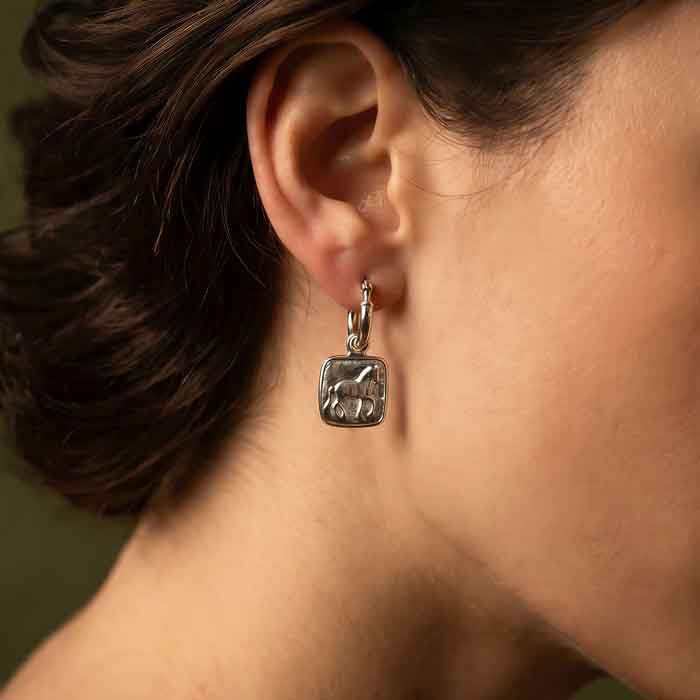 A pair of sterling silver hoop-style dressage horse earrings, shown on horse lover