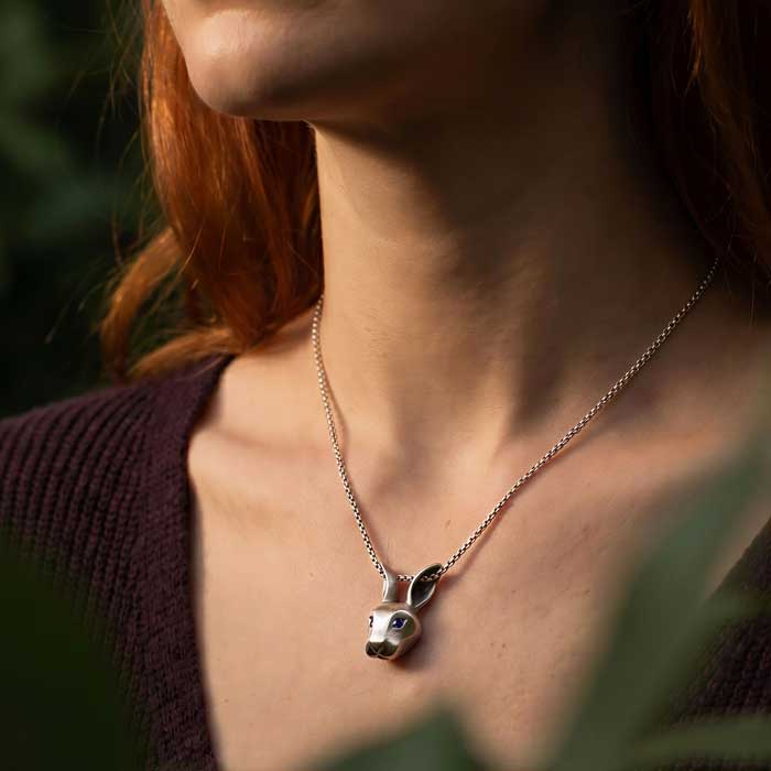 Jackrabbit Pendant Necklace sterling silver with blue sapphire eyes shown on neck of a woman