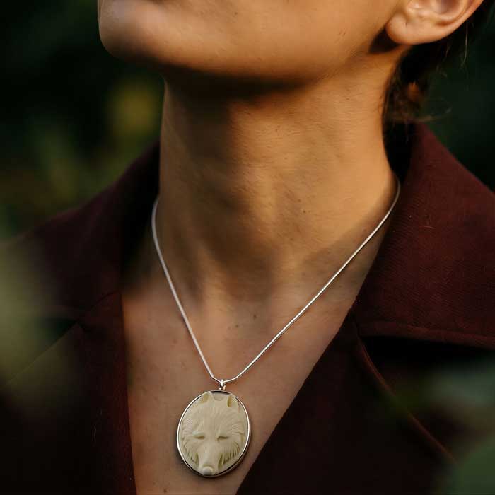 Carved Wolf Head Pendant Necklace set in sterling silver frame shown on woman's neck